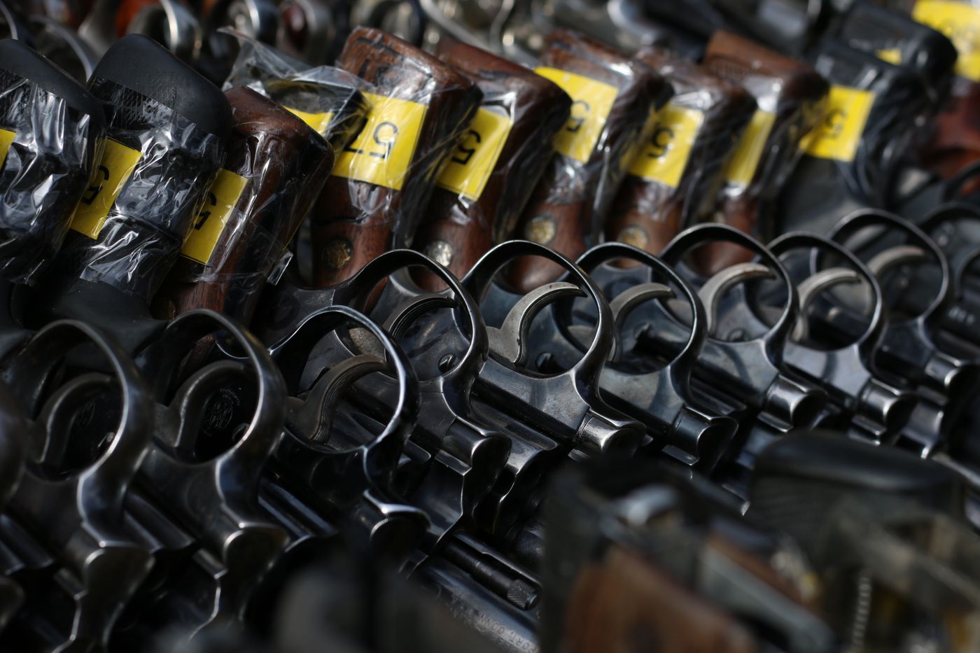 Close-up image of revolvers with yellow tags arranged on a rack.