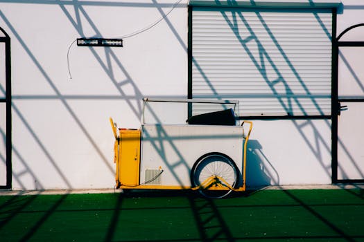 A solitary yellow trolley casting shadows on a white building exterior.