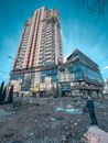 Man in Black Jacket Walking Near High Rise Building
