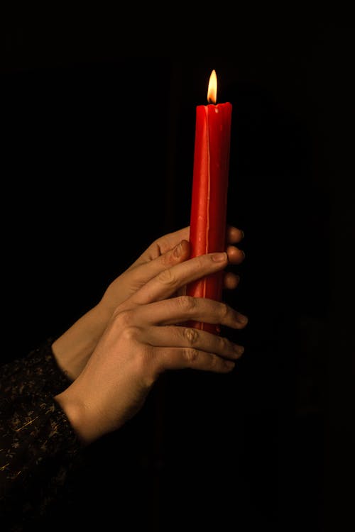 Ein Dramatisches Foto Der Frauenhände, Die Die Rote Kerze Halten