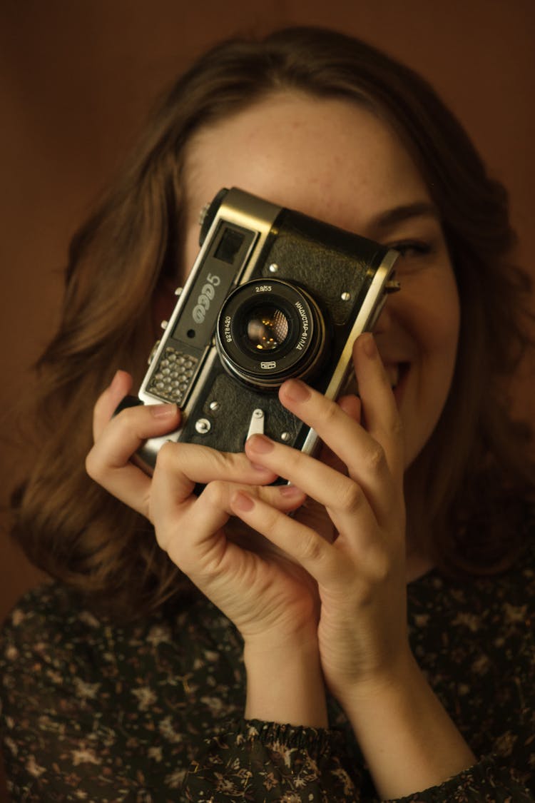 Portrait Of Woman Holding Vintage Camera In Front Of Her Face