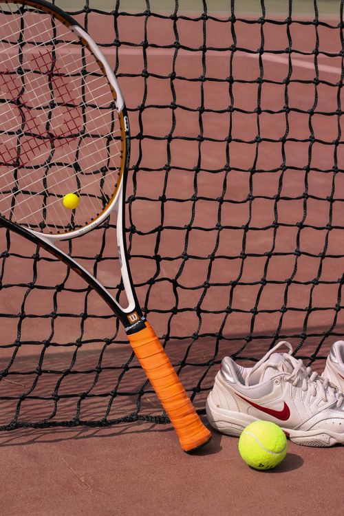 Free Tennis equipment including a racket, balls, and shoes on a clay court. Stock Photo