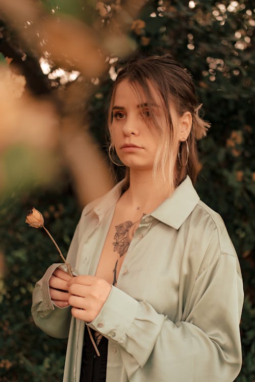 Woman in Gray Button-Up Shirt Holding a Flower