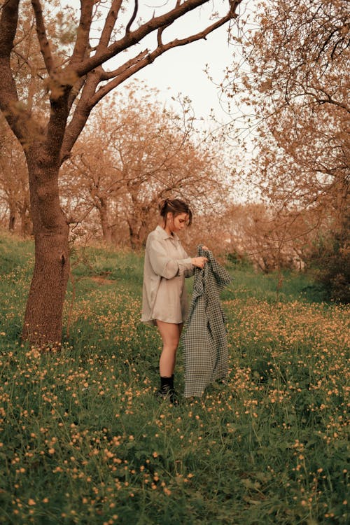 Beautiful Woman Holding a Coat while standing beside a Tree 
