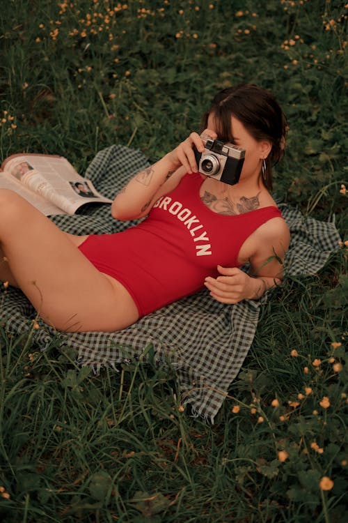 Woman in Swimsuit Lying on Grass with Camera