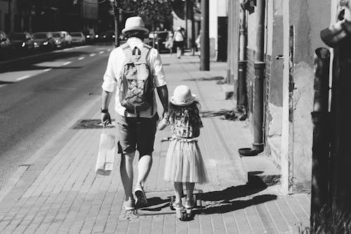 Free Man Holding Girl While Walking on Street Stock Photo