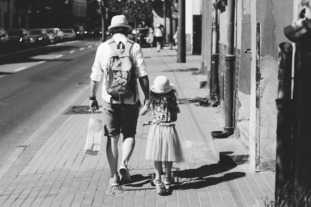 Man holding a girl while walking on the street. | Photo: Pexels