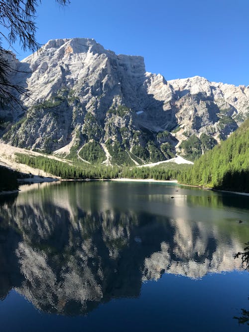 Lake Near Gray Rocky Mountain Under Blue Sky