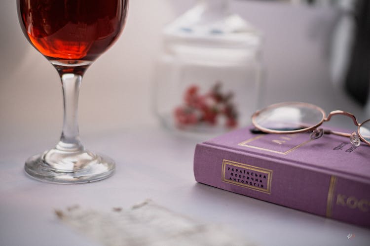 A Glass Of Wine Near A Book