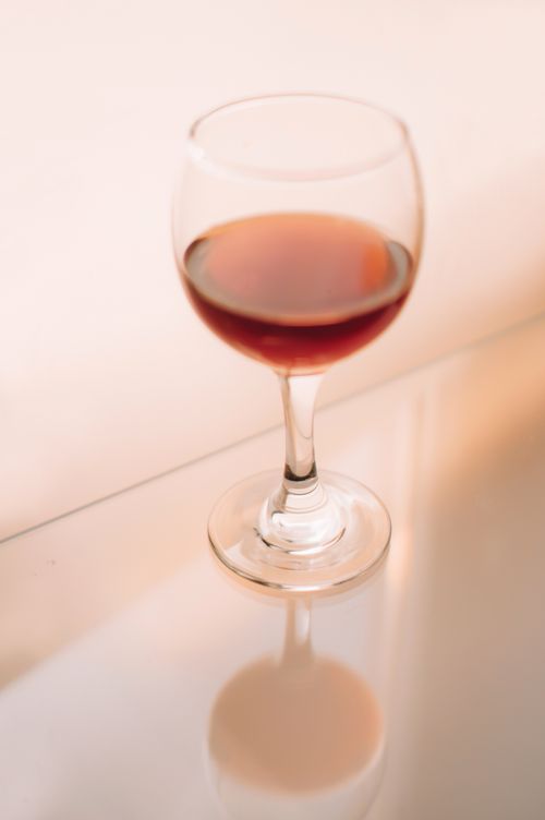Free Artistic shot of a red wine glass casting a reflection on a glossy surface. Stock Photo