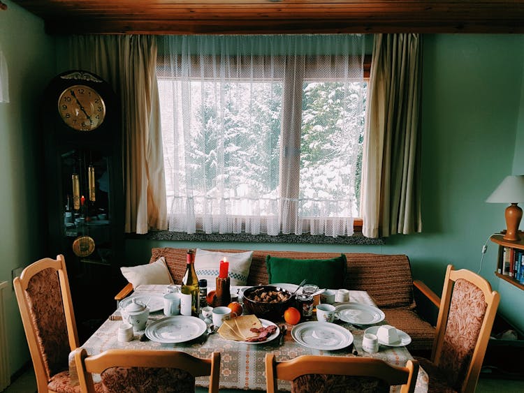 Arranged Table With Chairs And Plates Near Window