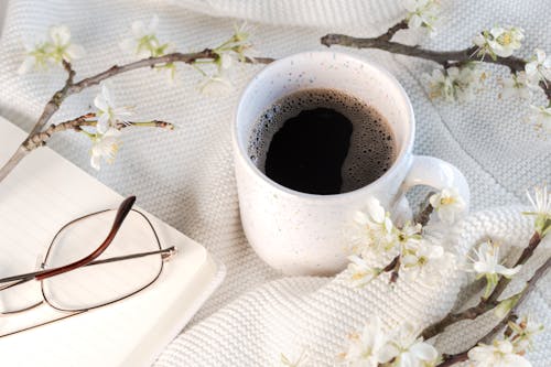 A Coffee on a Ceramic Mug Near the White Flowers