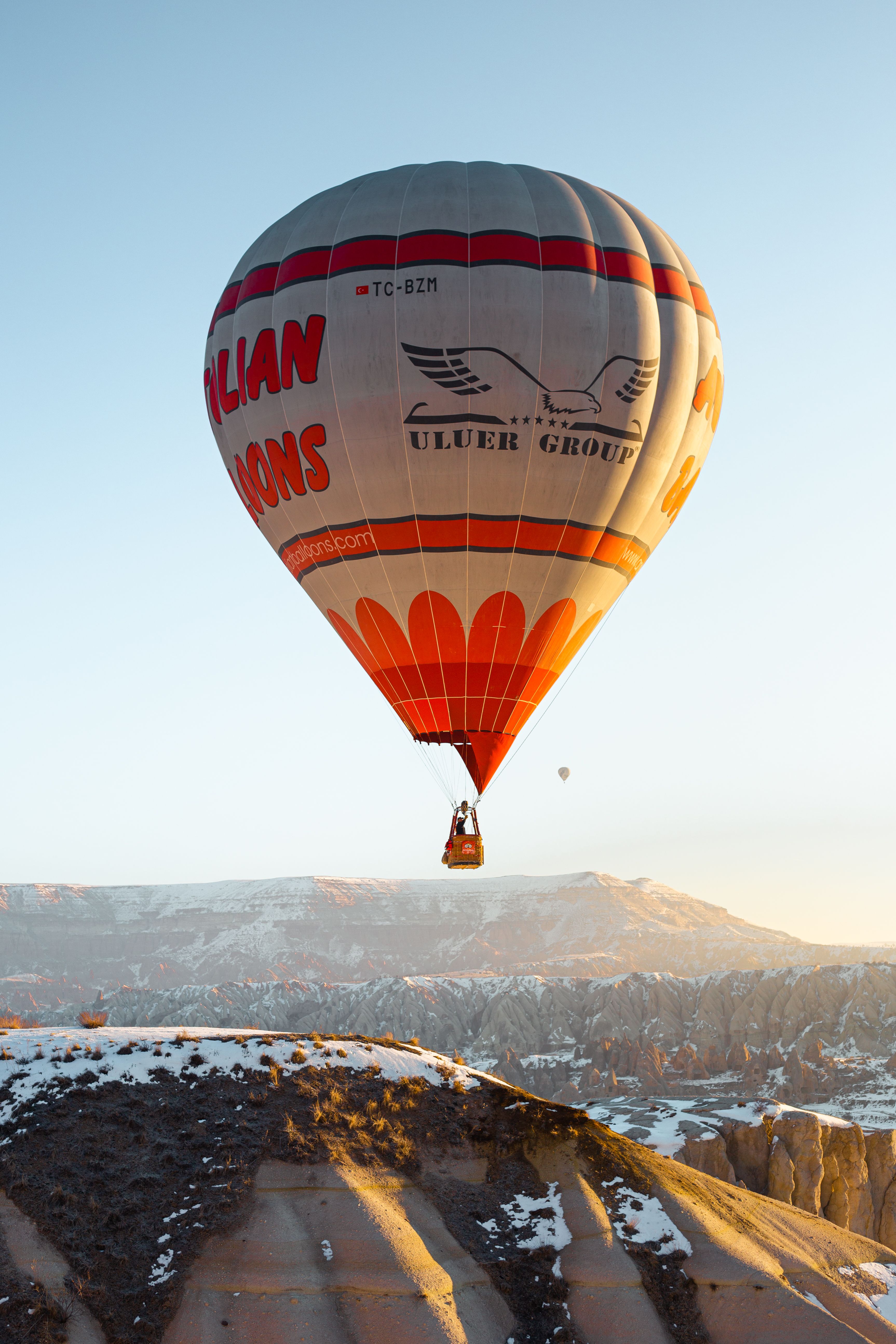 Breathtaking view of a hot air balloon soaring over Cappadocia's unique landscape at sunrise.