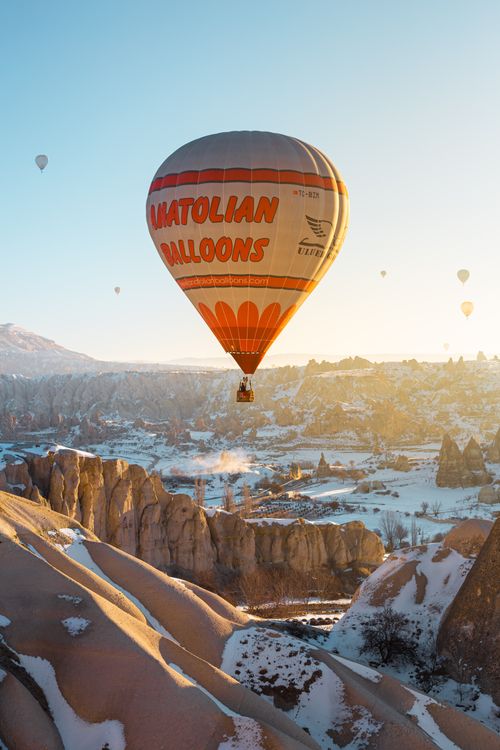 Free Breathtaking view of hot air balloons soaring over the snowy landscapes of Cappadocia at sunrise. Stock Photo