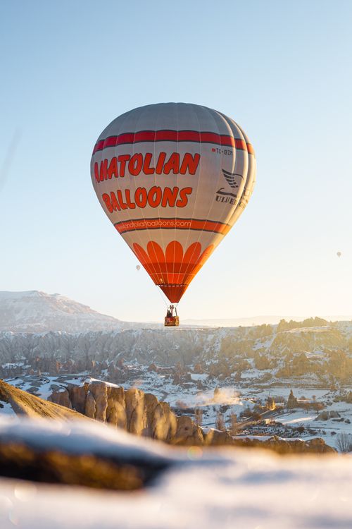 Free A dramatic hot air balloon drifts over the snowy landscapes of Cappadocia, Turkey during sunset. Stock Photo