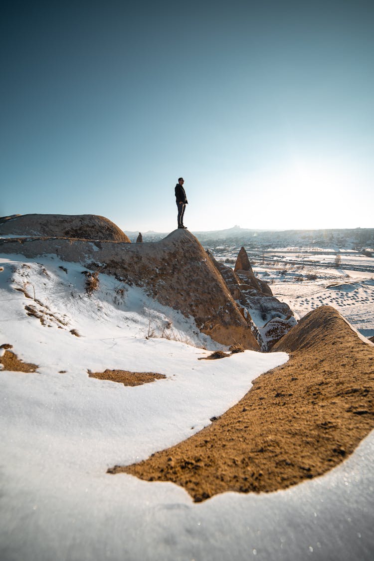 Man Standing On Rock In Winter