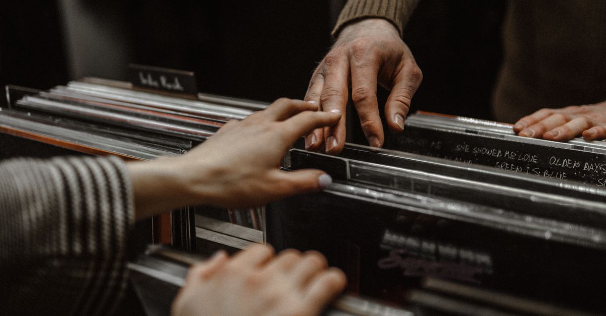 close-up of hands holding a vinyl record sleeve with a phone in the background
