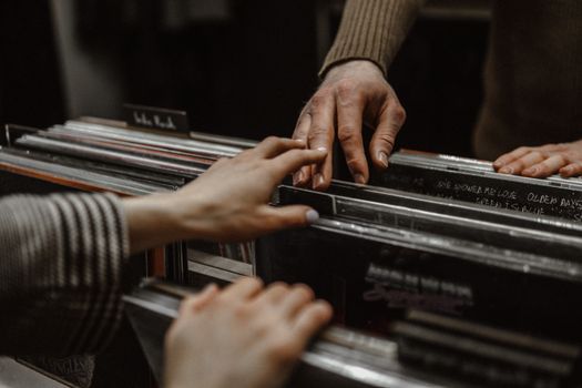 A close-up of a couple's hands browsing vinyl records, evoking intimacy and nostalgia.
