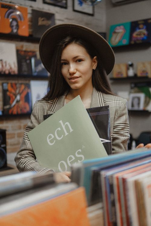 Free Woman holding vinyl records in a music store, showcasing a retro shopping experience. Stock Photo