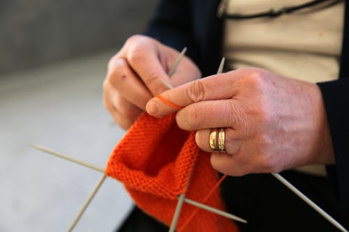 Person Holding a Red Yarn and Knitting