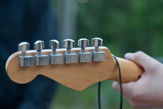 Detailed close-up of a guitar headstock with tuning pegs outdoors.