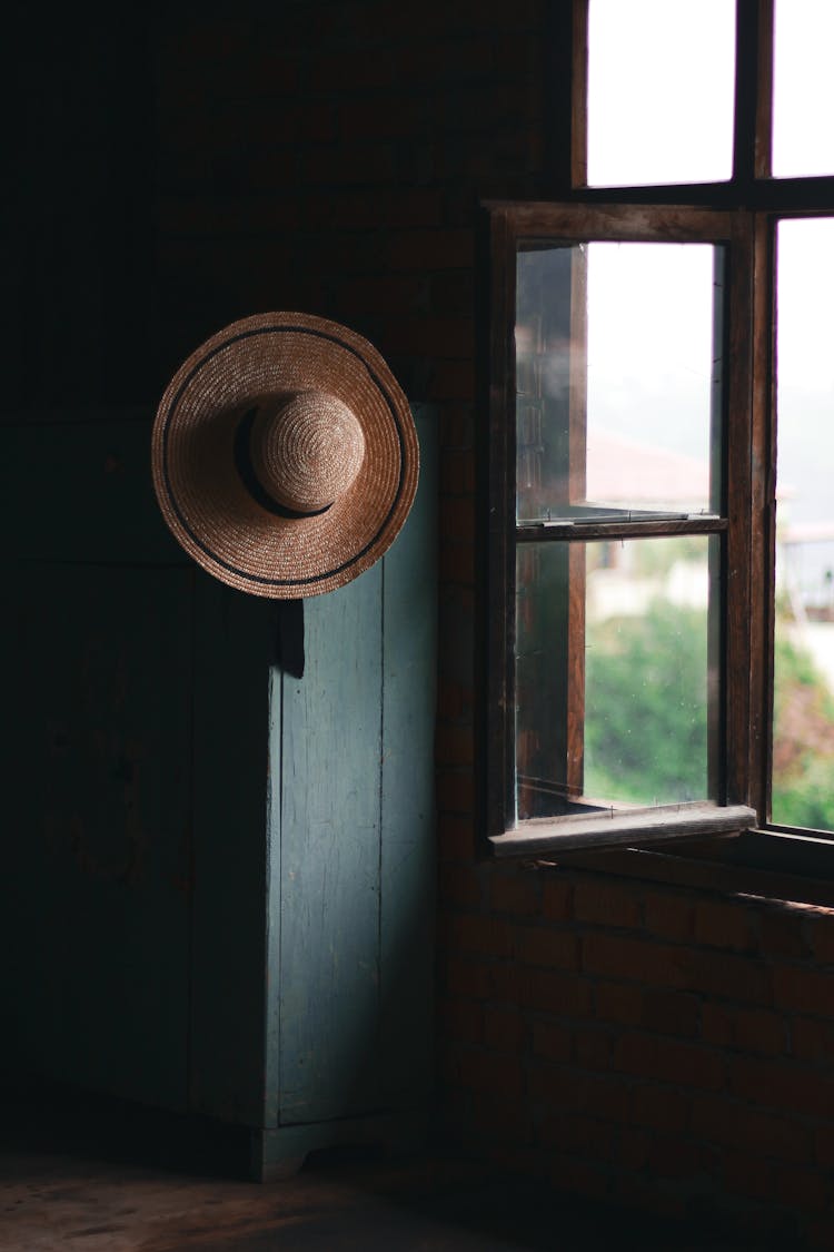 Straw Hat Hanging By Window In Hut