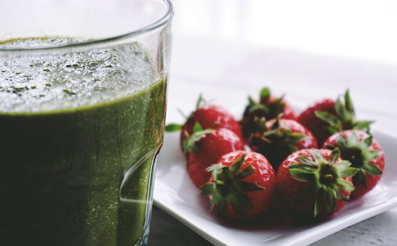 Close-up of a green smoothie and fresh strawberries on a white saucer.