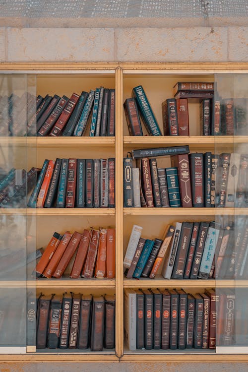 Assorted-title of Books Inside Brown Wooden Framed Glass Wall-mount Cabinet