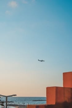 Airplane soaring above Tel Aviv skyline at sunset, highlighting the city's vibrant contrast.