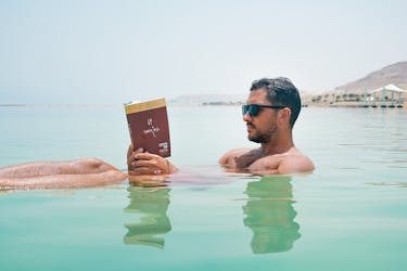 Man Wearing Sunglasses Reading Book on Body of Water, Israel
