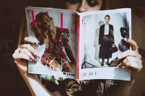 Free A woman reading a fashion magazine indoors. Ideal for lifestyle and fashion content. Stock Photo