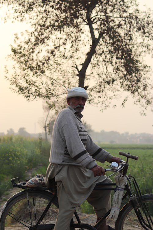 Elderly Man in Gray Sweater and Turban Riding a Bicycle