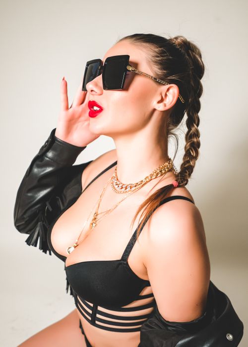 Free Fashionable woman in sunglasses, braided hair, and bold jewelry posing confidently. Stock Photo