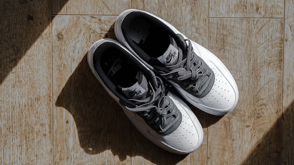 White leather trainers laid out on a wooden floor — photo by Nathan J Hilton on Pexels