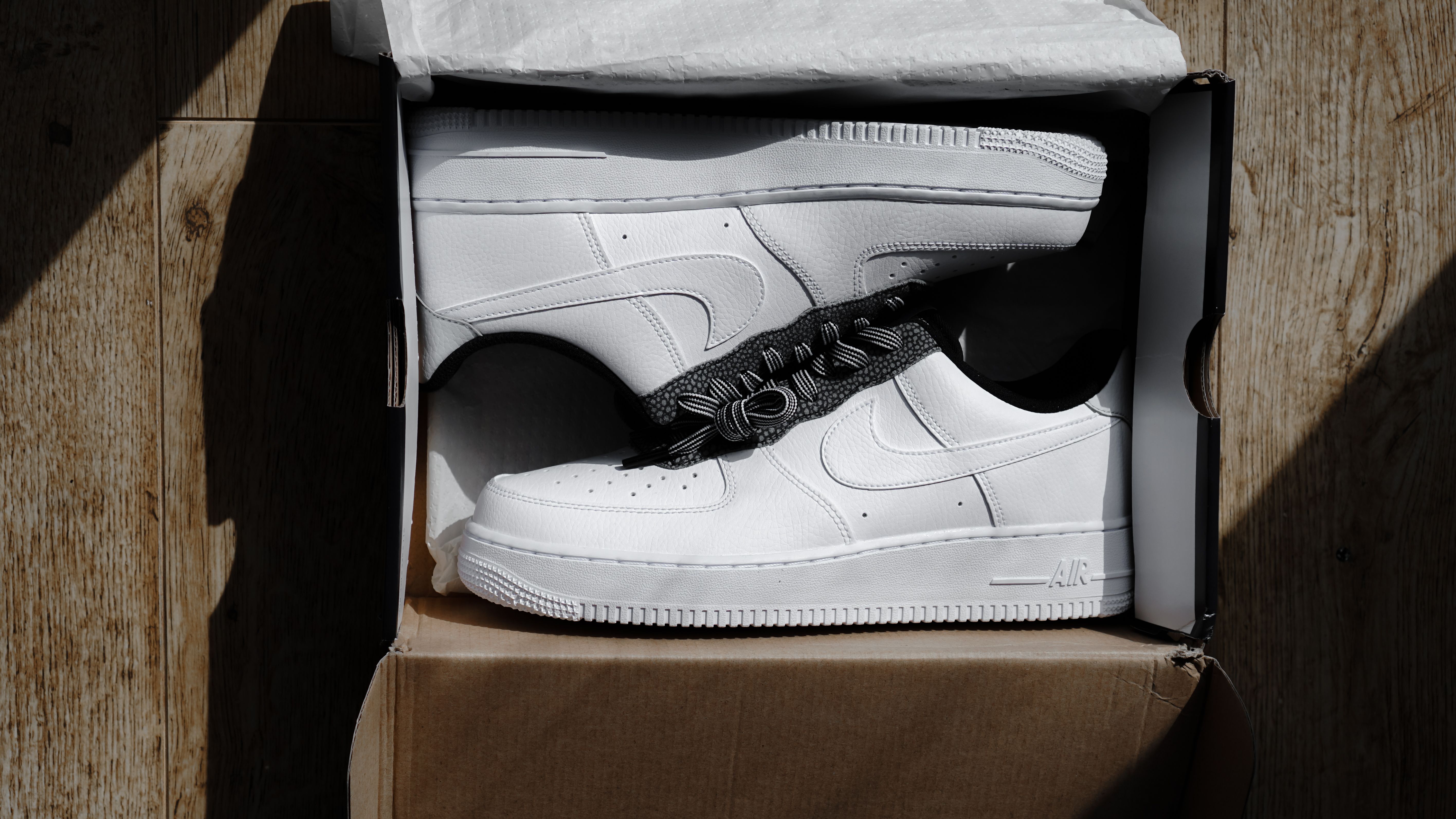 A pair of clean white sneakers displayed in an open box, a footwear product needing a specialist tech pack