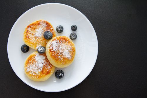Free Top view of pancakes with blueberries and powdered sugar on a white plate. Stock Photo