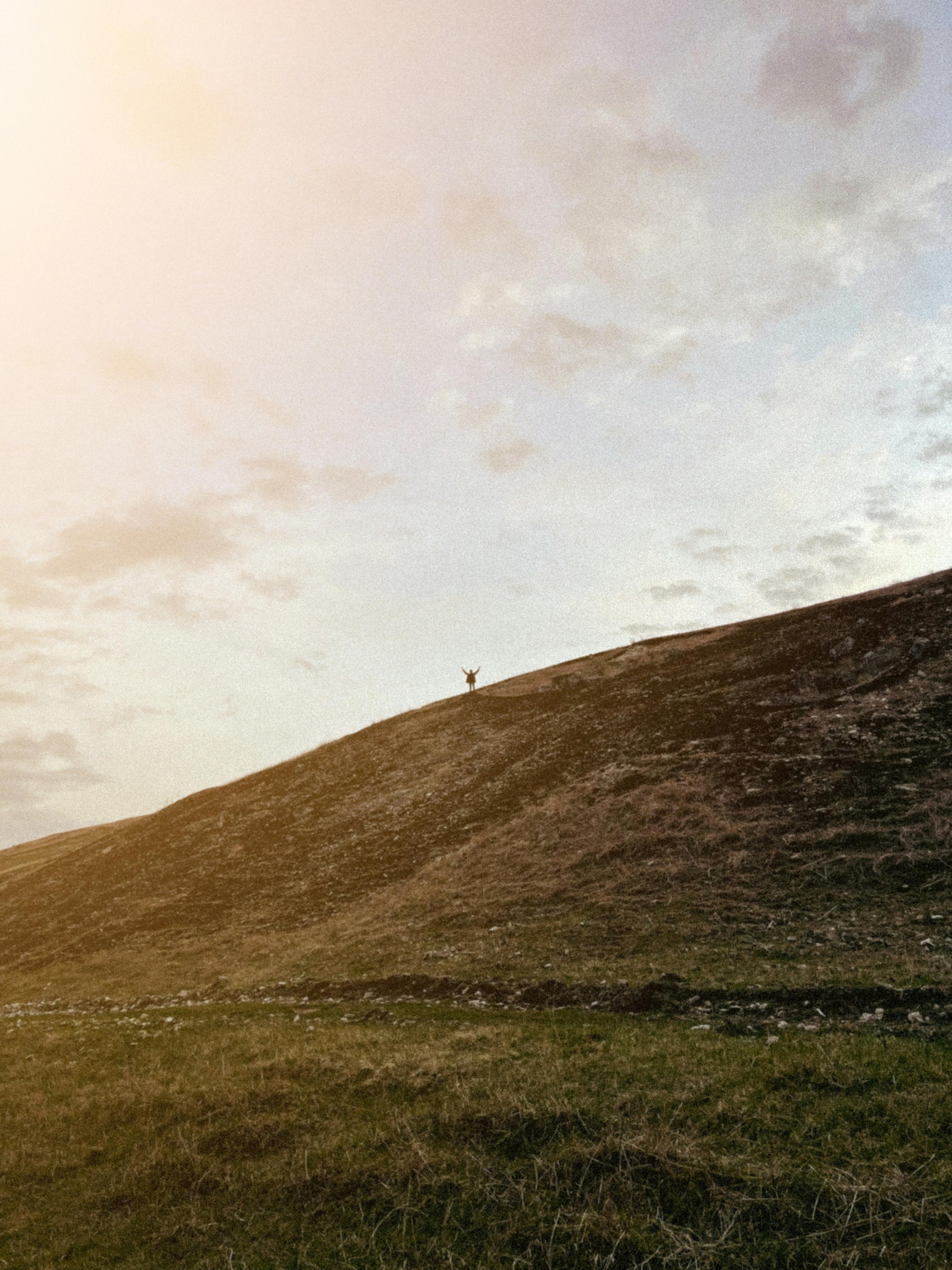 person standing on a hill with arms raised