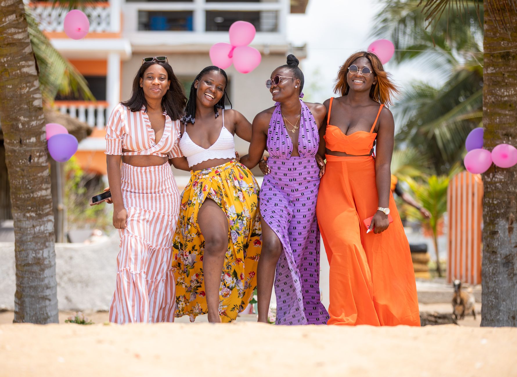 summer beach party sahel — Four friends having fun at a vibrant beach party with colorful balloons and palm trees.