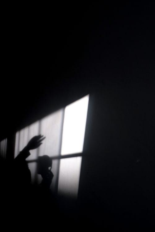 Free Intriguing silhouette of a hand casting a shadow through a window in a dark room. Stock Photo