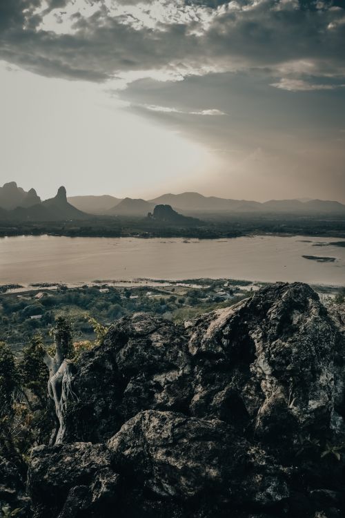 Free Scenic landscape showcasing a dramatic sky over mountains, river, and rocks at dusk. Stock Photo