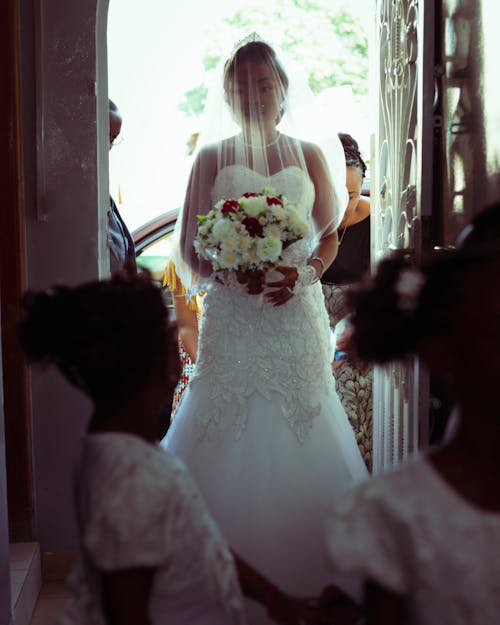 A Beautiful Bride in White Wedding Gown while Holding a Bouquet of Flowers