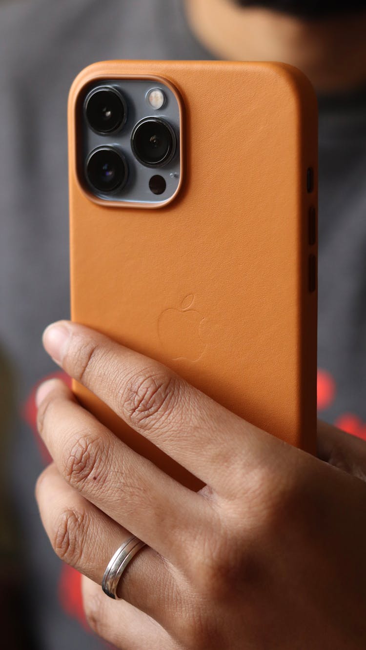 A Person Holding An Iphone With An Orange Case