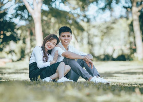 A Couple Smiling while Sitting on the Grass