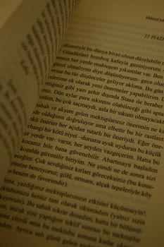 Close-up shot of an open book showing text on pages, creating a warm reading ambiance. — photo by Enes Sözen