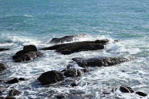 Free Waves crash on rocks along the coast, showcasing the dynamic beauty of the ocean. Stock Photo