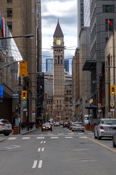 View of Toronto's Old City Hall clock tower on a bustling downtown street.