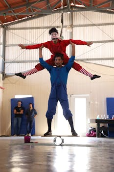 Two acrobats performing a skilled balance act indoors, showcasing flexibility and vibrant costumes.
