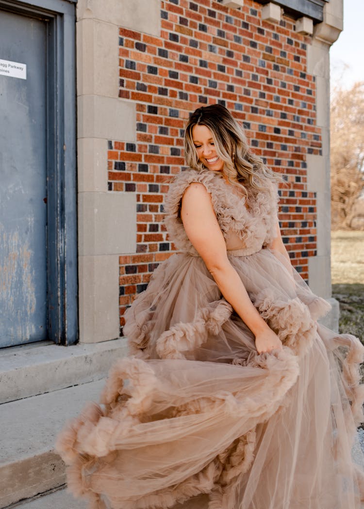 Smiling Woman Standing In Beige Gown On A Doorway