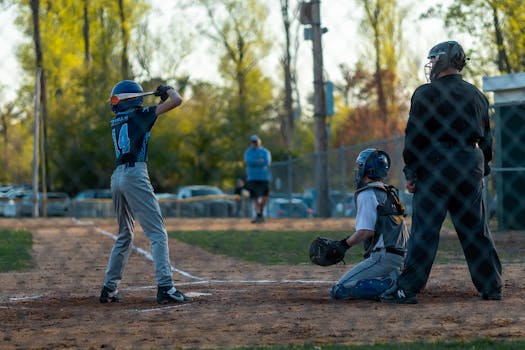 A young baseball player at bat during a lively spring game with catcher and umpire ready.