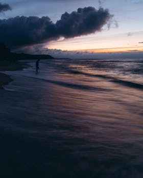 A serene oceanside scene with waves and dramatic clouds at sunset. Perfect for nature lovers.